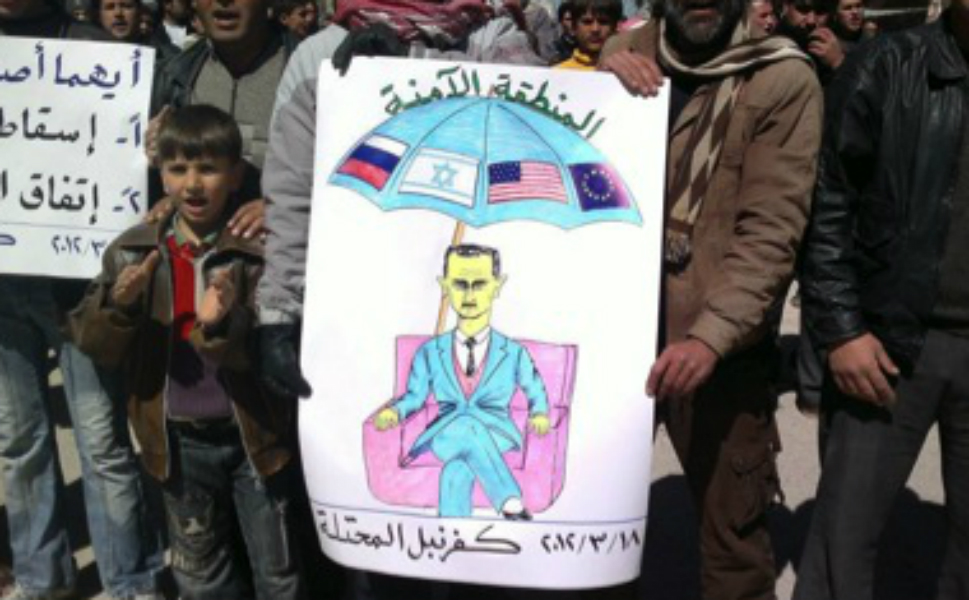 Асад под зонтиком с надписью Зона безопасности. На зонтике флаги России, Израиля, США и Евросоюза - стран, которые или помогают Асаду, как Россия, или не устраивают против него вооружённой агрессии, чего хотят повстанцы.